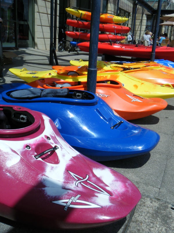 Colorful kayaks lined up on a sunny sidewalk.
