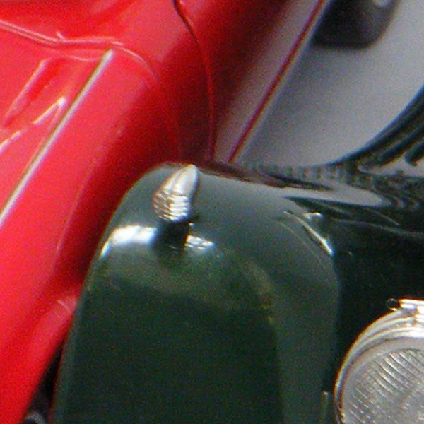 Close-up of a screw on a red and green surface.