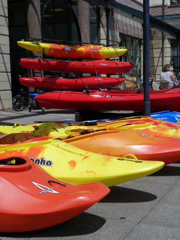 Stacked colorful kayaks on a sunny day.