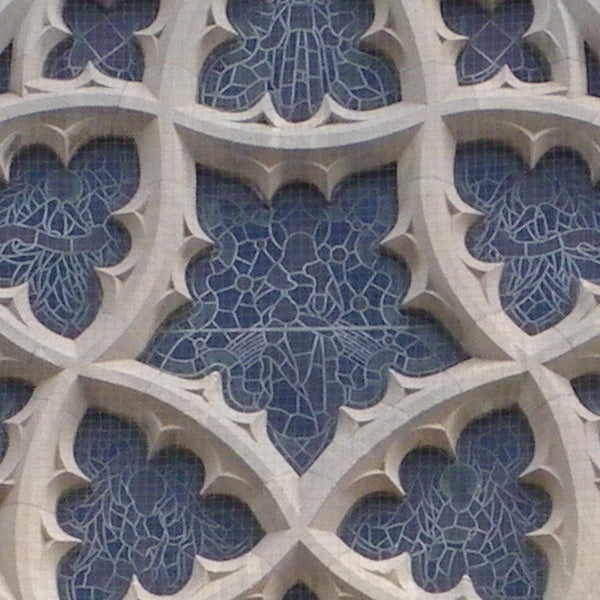 Close-up of intricate stone lattice work pattern on a facade.