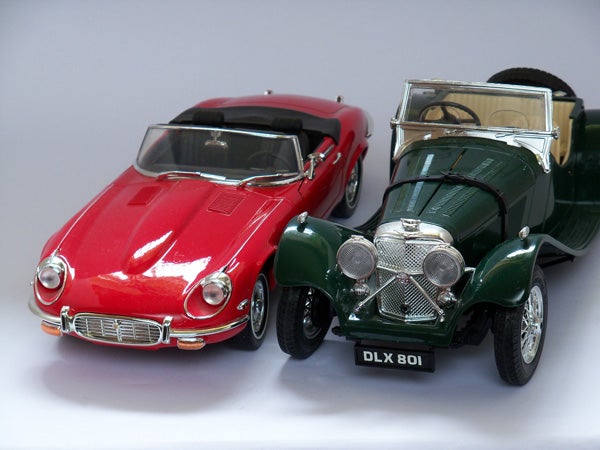 Toy red Jaguar E-Type and green classic car models.