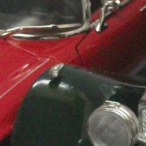 Close-up of a vintage red car's shiny chrome details.