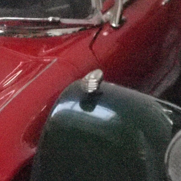 Close-up of a vintage red car's curvature.