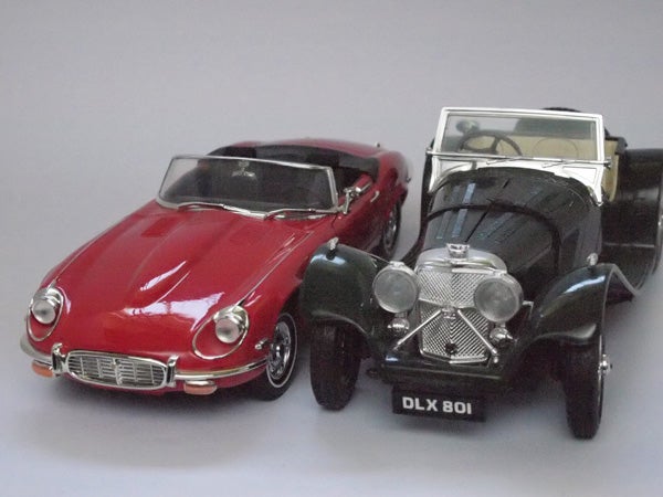 Two vintage model cars, a red Jaguar E-Type and black convertible.