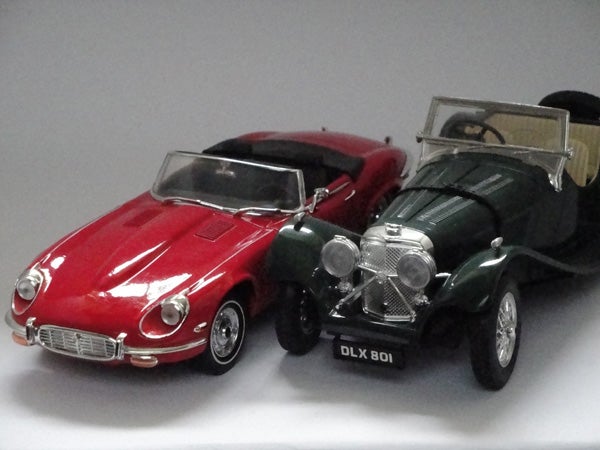 Two vintage toy car models on display.