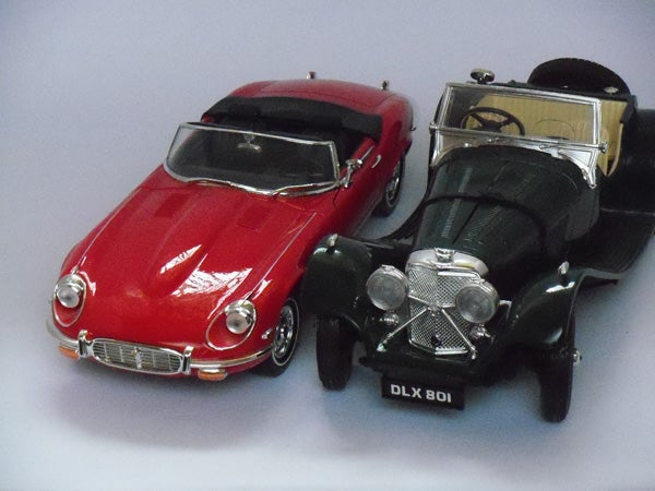 Toy model cars on display, red Jaguar E-Type and black classic car.