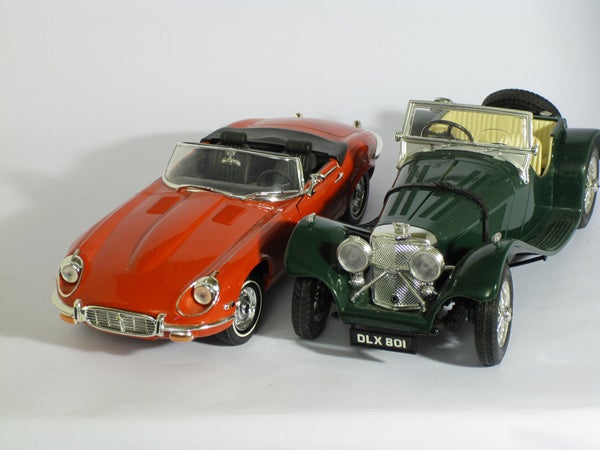 Two model cars, a red Jaguar E-Type and a green classic roadster.