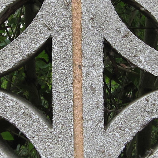 Close-up of rusted garden bench armrest with foliage background