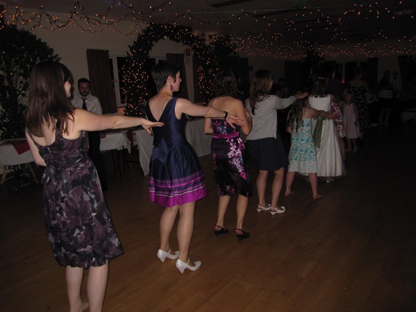 People dancing at an indoor event with string lights.