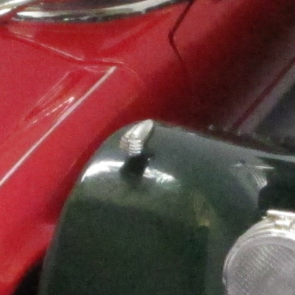 Close-up photo of red car's shiny surface with a reflection