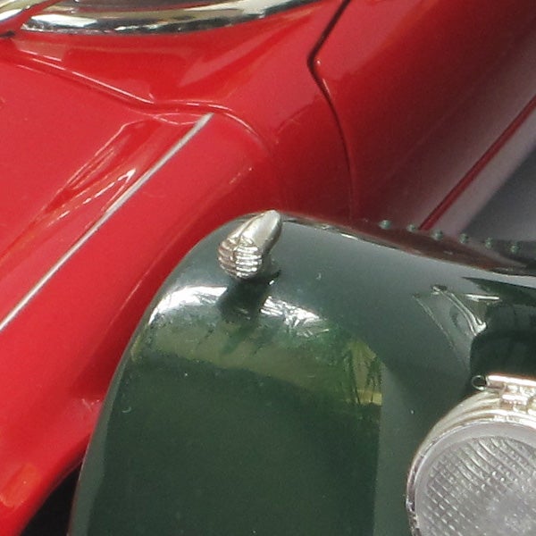 Close-up of a red and green toy car hood and headlight.