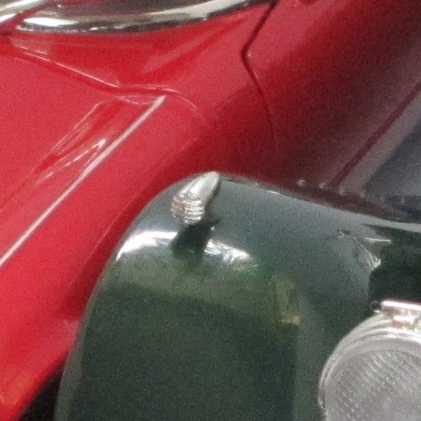 Close-up of a red car's bodywork and headlight.