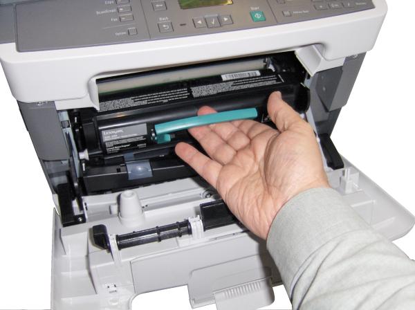 Hand replacing toner cartridge in Lexmark X204n printer.