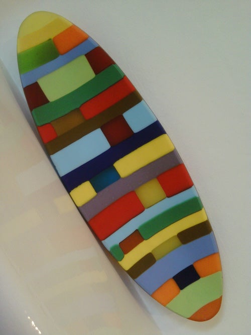 Colorful abstract surfboard art installation on white background.