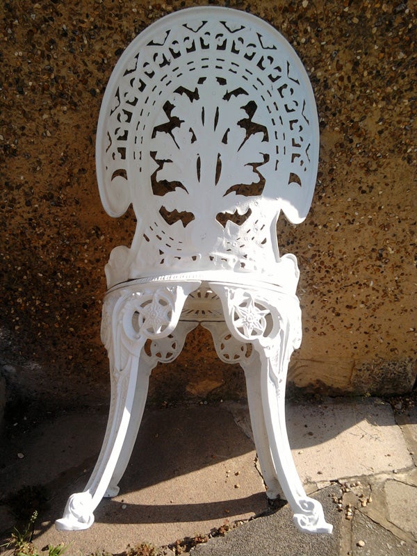 White ornate plastic chair against a concrete background.