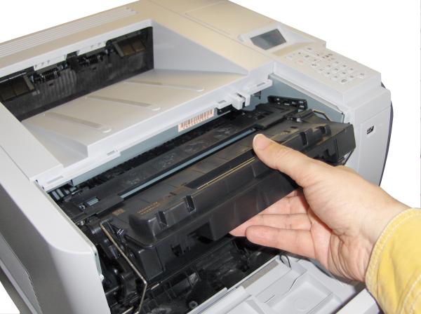 Person changing toner cartridge in HP LaserJet P3015X printer.