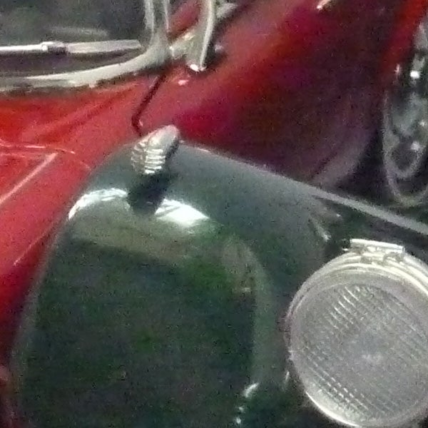 Close-up of a classic motorcycle's headlamp and fuel tank.