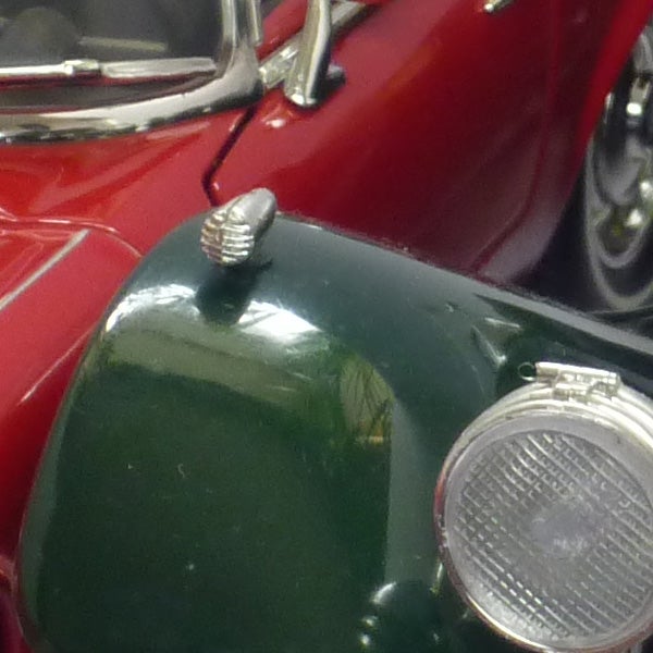 Close-up of a green vintage car's headlight and fender.