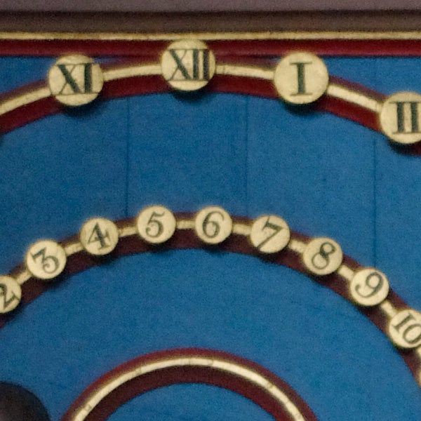 Close-up of a colorful clock face with Roman numerals.