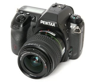 Pentax K-7 DSLR camera with zoom lens on white background.