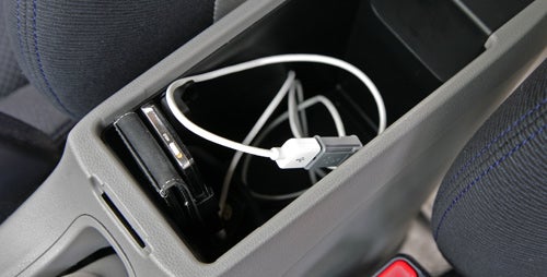 Honda Insight's center console with charging cables and storage.Hand plugging in USB cable in Honda Insight console