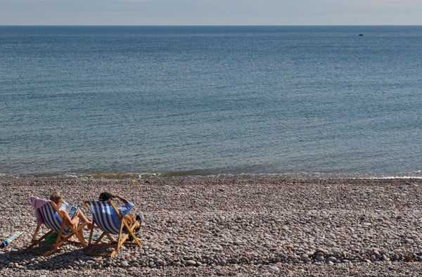 Two people relaxing on beach chairs by the sea.