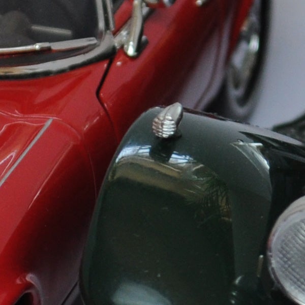 Close-up of a toy car's side mirror and headlight.