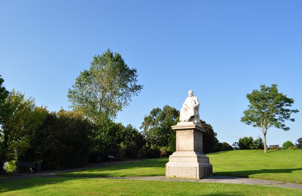 Statue in a park on a sunny day, clear blue sky.