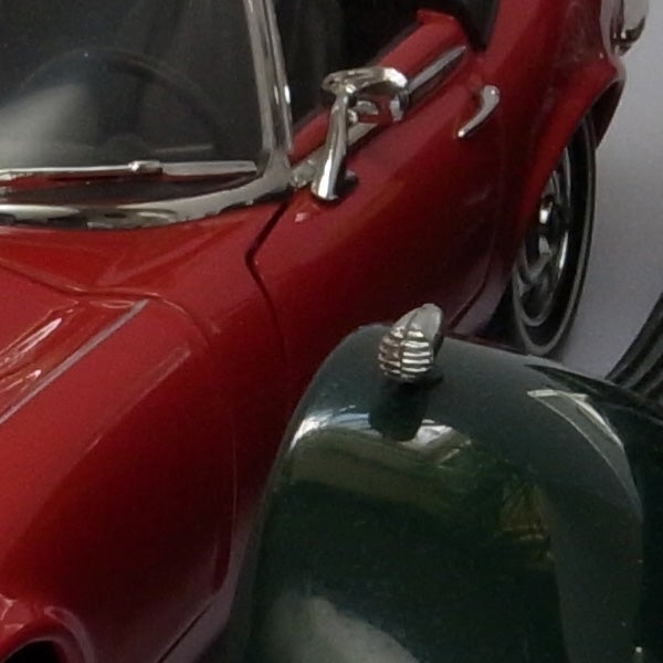 Close-up of a red and green vintage toy car models.