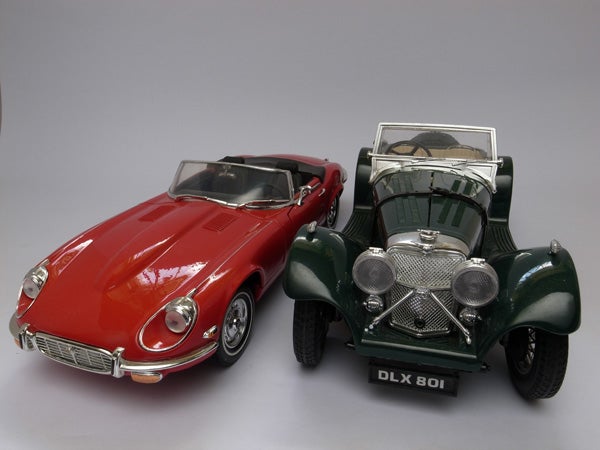 Two model cars, a red roadster and a green vintage convertible.