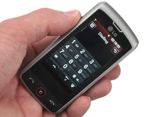 Hand holding an LG GW520 mobile phone displaying dial screen.
