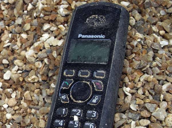 Panasonic rugged DECT phone on gravel surface.