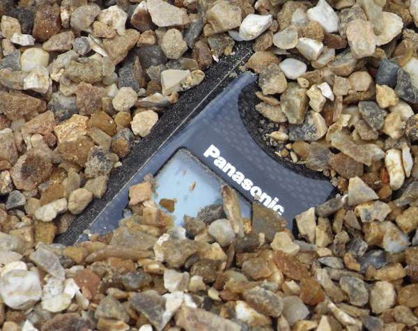 Panasonic rugged DECT phone partially buried in gravel.