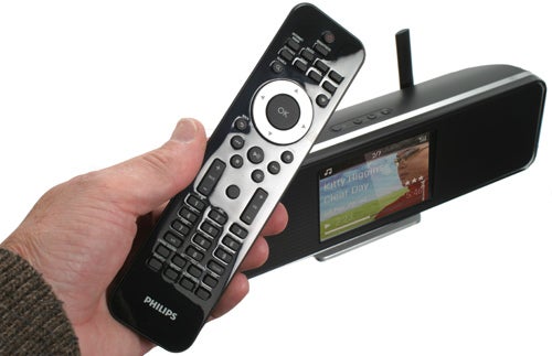 Hand holding remote control with Philips Streamium NP2900 in background.
