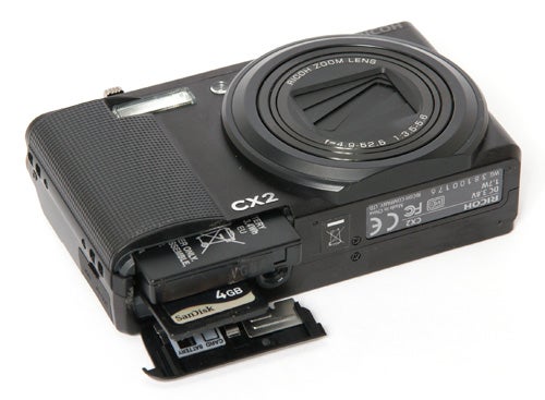 Ricoh CX2 camera with open battery and memory card compartment.