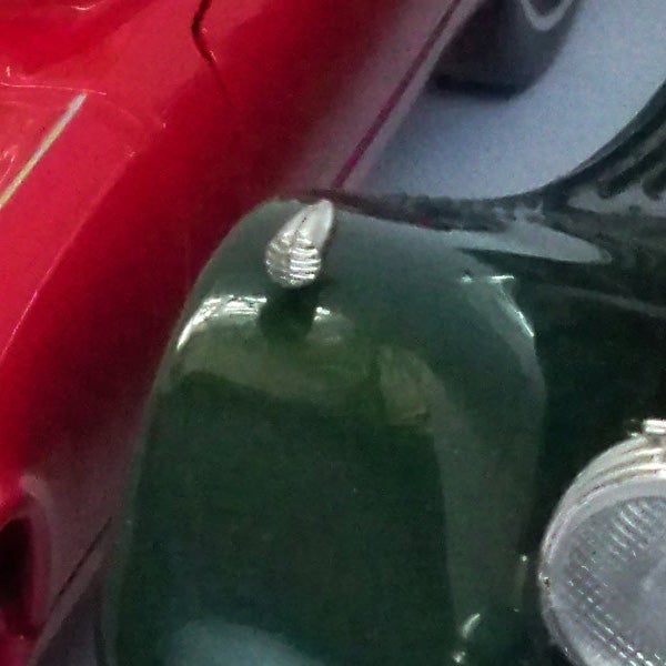 Close-up view of a toy car reflected in shiny surface.