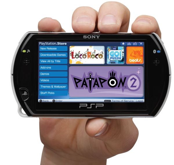 Hand holding a Sony PSPgo displaying its menu screen.