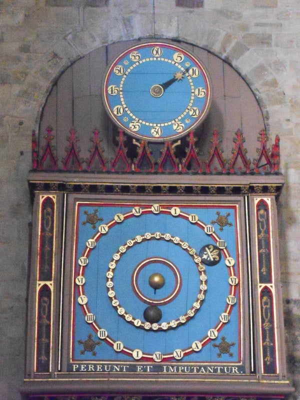 Ornate astronomical clock on a stone wall.
