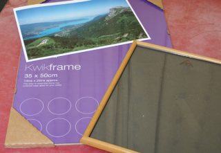 Picture frame with poster and landscape photo on table.