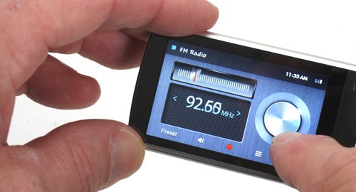 Hands holding Samsung YP-R1 showing FM radio screen.