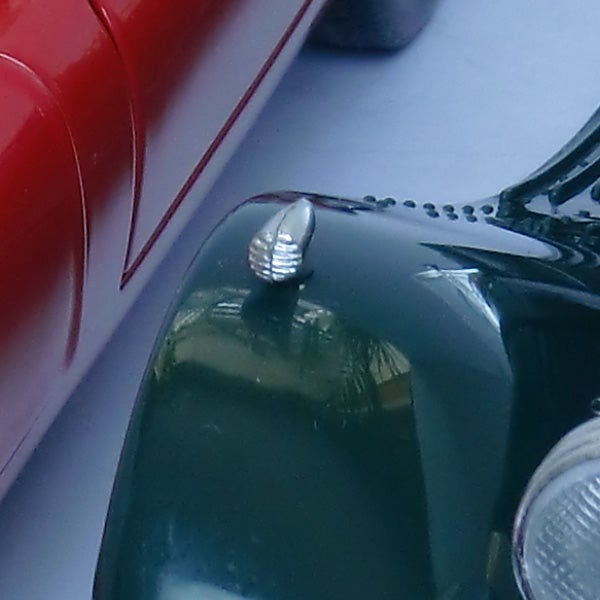 Close-up of a vintage toy car hood and headlight.