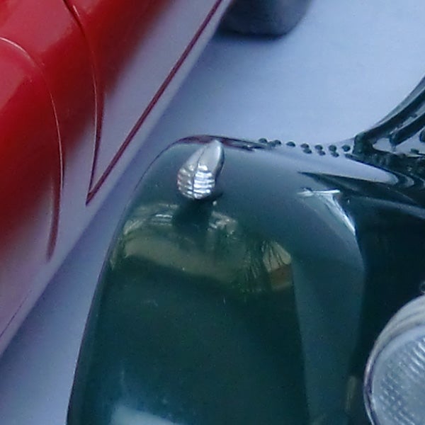 Close-up of a green toy car's front corner with shiny details