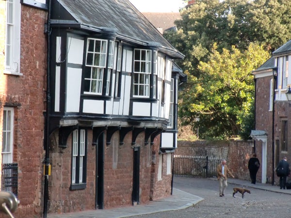 Tudor style building with a person and dog on street.