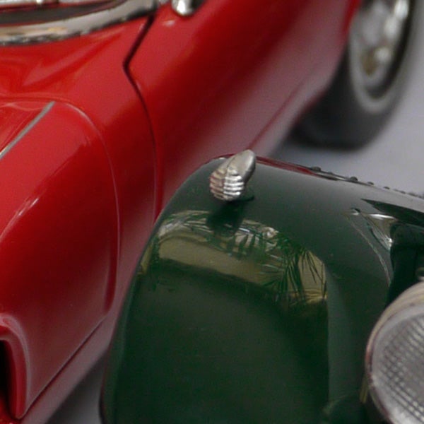 Close-up of two toy cars, red and green, with reflective surfaces