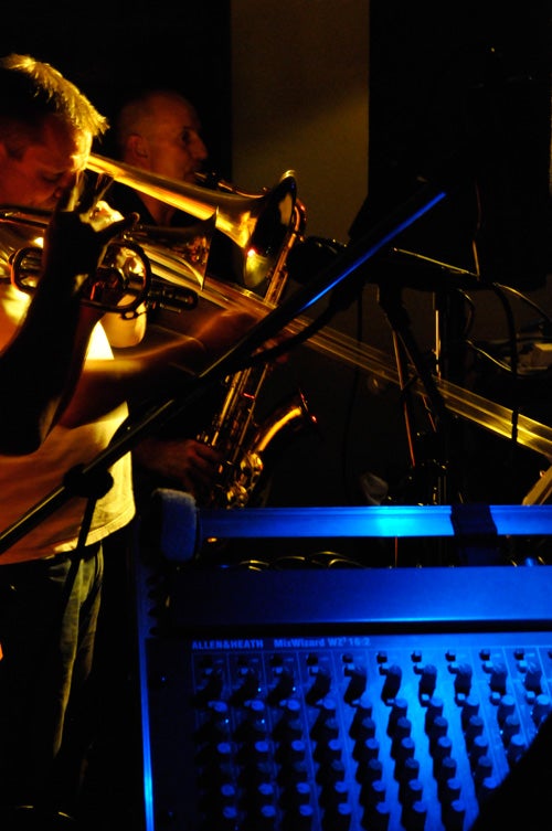 Musicians performing with a trumpet and sound mixer board.
