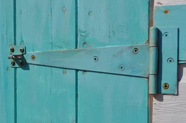 Turquoise wooden door with a metal latch.