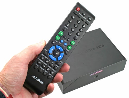 Hand holding remote control with A.C.Ryan Playon!HD Media Player in the background.