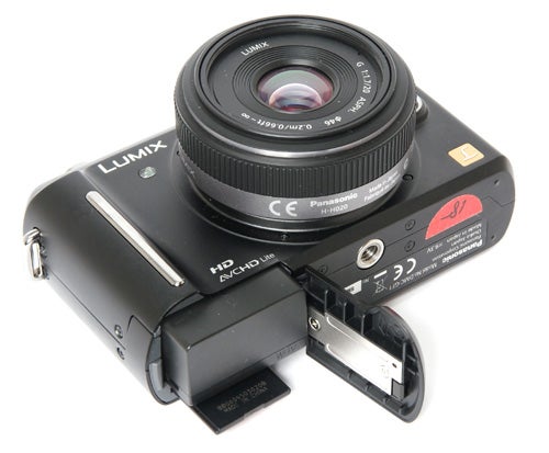 Panasonic Lumix DMC-GF1 camera with open battery compartment.