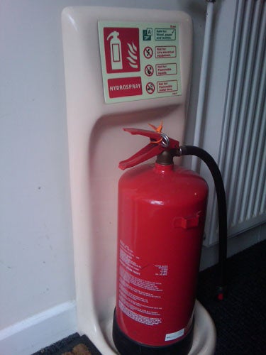 Fire extinguisher standing in holder with safety instructions.