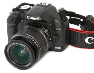 Canon EOS 500D DSLR camera with lens and strap.